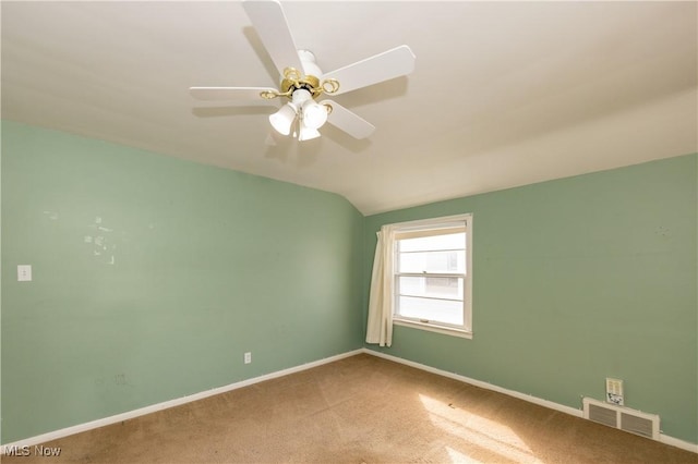 carpeted empty room featuring visible vents, a ceiling fan, baseboards, and vaulted ceiling