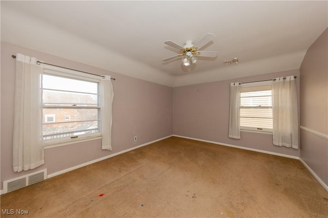 carpeted empty room with visible vents, baseboards, lofted ceiling, and ceiling fan