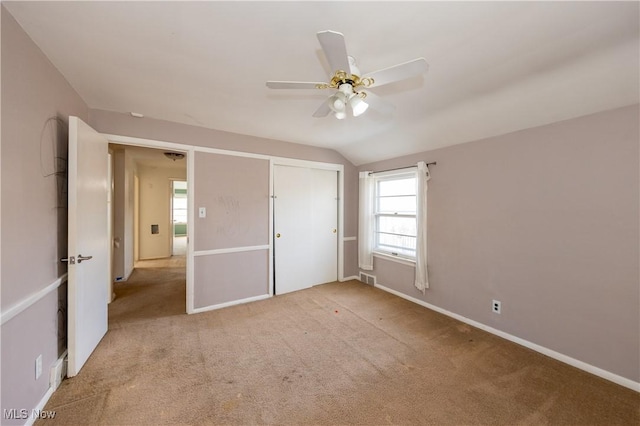 unfurnished bedroom featuring visible vents, lofted ceiling, a closet, carpet, and baseboards