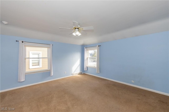 carpeted empty room with visible vents, baseboards, and a ceiling fan