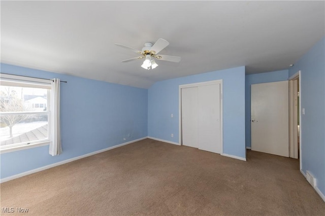 unfurnished bedroom with lofted ceiling, carpet, a closet, and baseboards