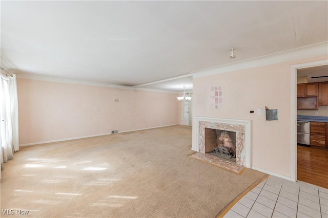 unfurnished living room with a high end fireplace, crown molding, light tile patterned floors, baseboards, and a chandelier