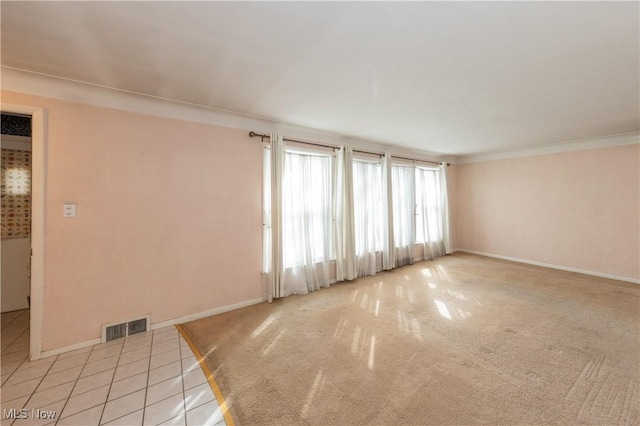 empty room with tile patterned flooring, visible vents, baseboards, and ornamental molding