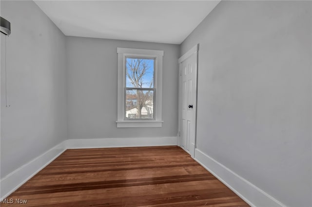 spare room featuring baseboards and wood finished floors