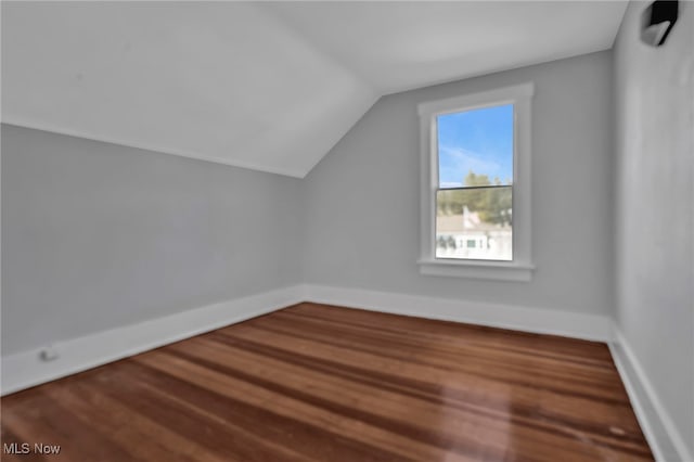 bonus room with wood finished floors, baseboards, and vaulted ceiling