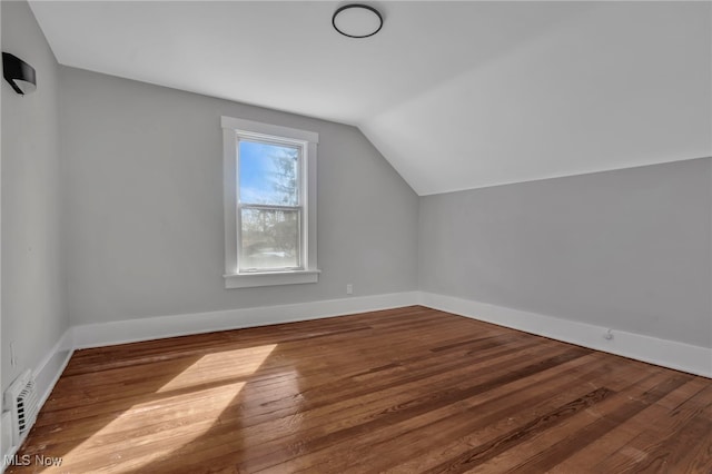 bonus room with vaulted ceiling, visible vents, baseboards, and wood finished floors