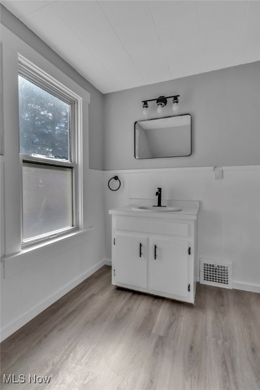 bathroom with visible vents, baseboards, a wainscoted wall, wood finished floors, and vanity