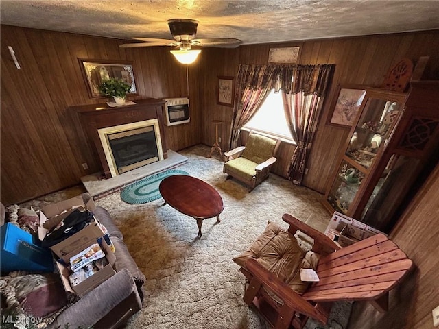 living room featuring a glass covered fireplace, wooden walls, heating unit, and carpet flooring