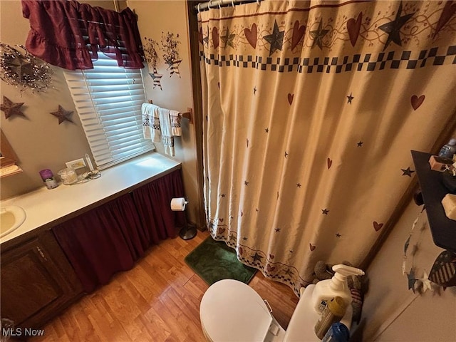 full bath featuring curtained shower, wood finished floors, and a sink