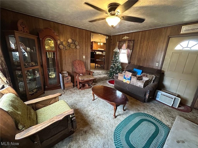 carpeted living room with wooden walls, a textured ceiling, ceiling fan, and a wall unit AC