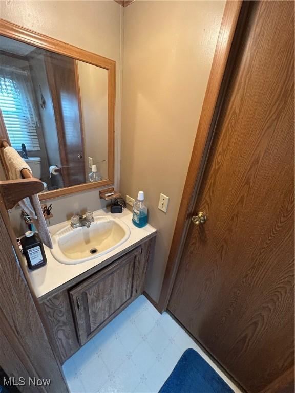 half bath with tile patterned floors, toilet, and vanity