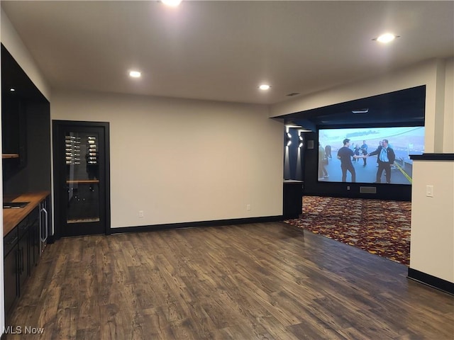 cinema room with dark wood finished floors, recessed lighting, and baseboards