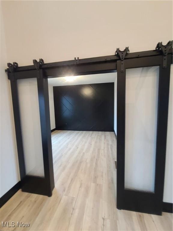 interior space with a barn door, wood finished floors, and baseboards