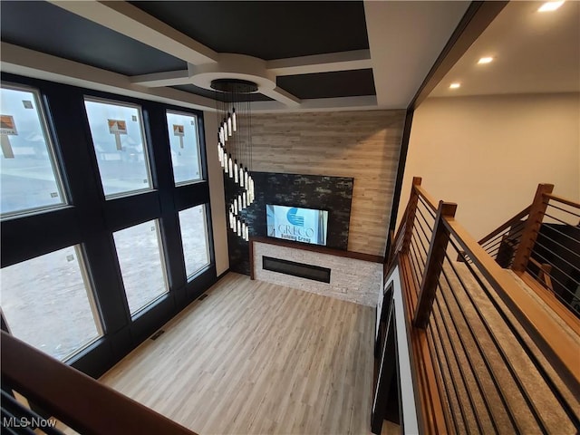 unfurnished living room featuring stairs, a glass covered fireplace, wood finished floors, and a healthy amount of sunlight