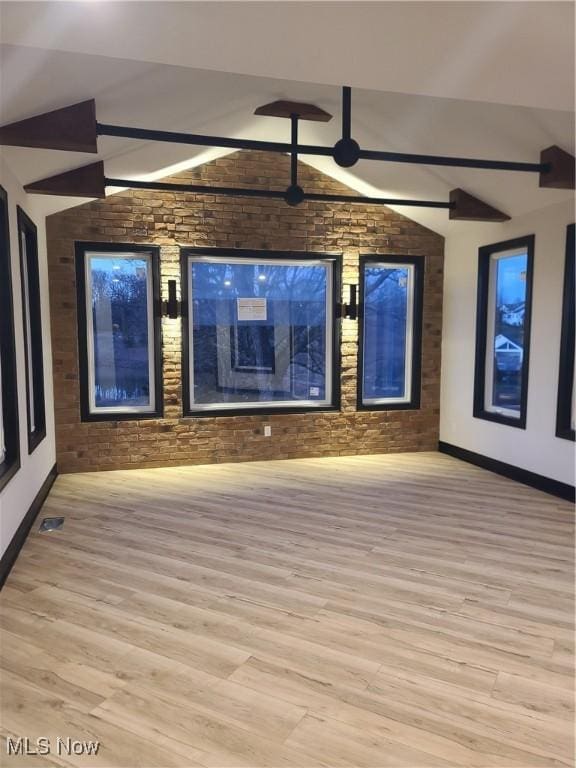 unfurnished living room with vaulted ceiling, light wood-style flooring, baseboards, and visible vents