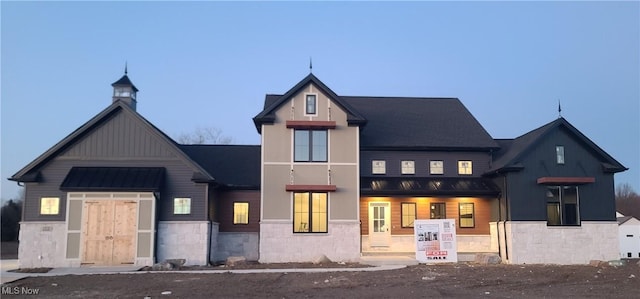 view of front of property with stone siding, board and batten siding, metal roof, and a standing seam roof