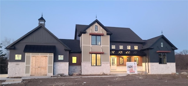 view of front facade with stone siding and a standing seam roof