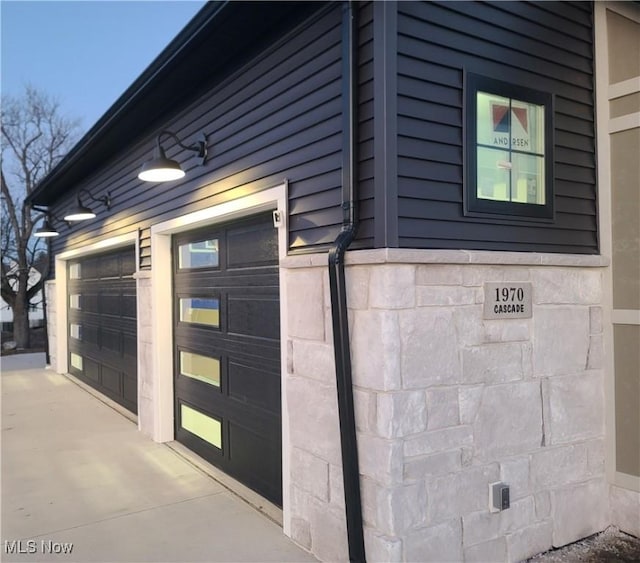 exterior space with a garage and stone siding