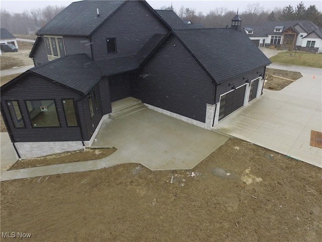 view of front of house featuring concrete driveway and a shingled roof