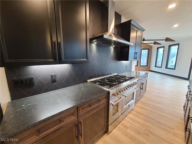 kitchen featuring wall chimney exhaust hood, double oven range, tasteful backsplash, and light wood finished floors