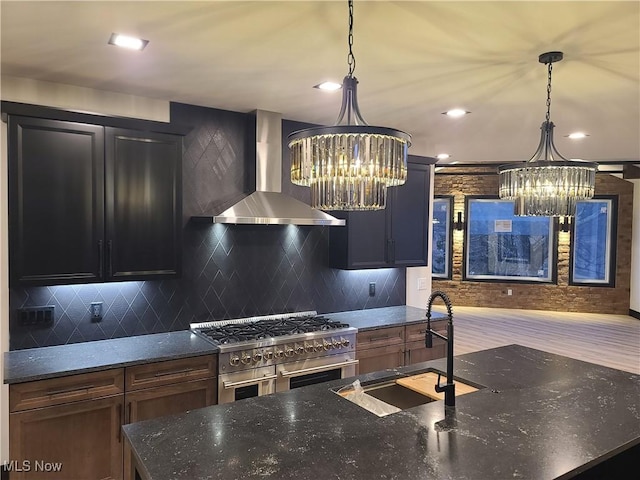 kitchen featuring range with two ovens, a chandelier, wall chimney exhaust hood, and a sink