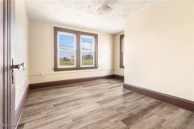 empty room featuring wood finished floors, baseboards, and a textured ceiling