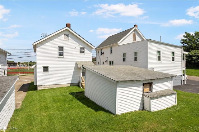 back of house with a yard and a chimney