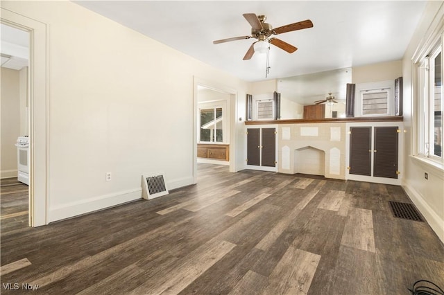 unfurnished living room with visible vents, a ceiling fan, baseboards, and dark wood-style flooring