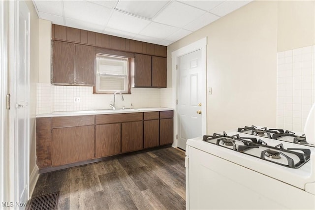 kitchen featuring tasteful backsplash, light countertops, white gas range, dark wood-style floors, and a sink