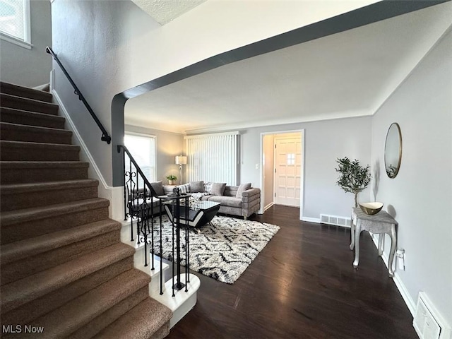 living area with dark wood-style floors, stairway, baseboards, and visible vents