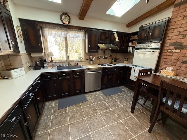 kitchen featuring a sink, decorative backsplash, white appliances, and vaulted ceiling with skylight