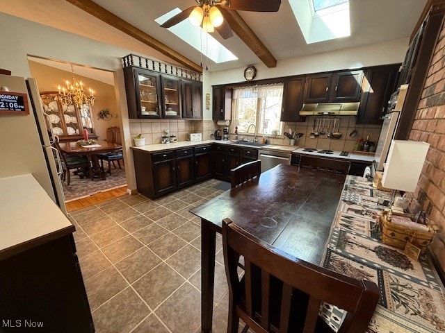 kitchen with freestanding refrigerator, under cabinet range hood, dishwasher, lofted ceiling with skylight, and tasteful backsplash