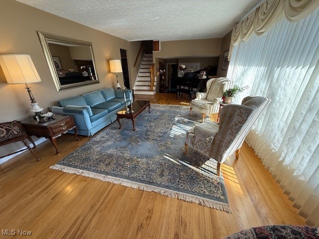 living area with stairway, a textured ceiling, and wood finished floors