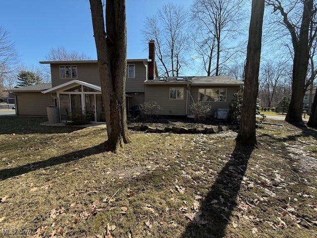 rear view of house featuring a sunroom and a chimney