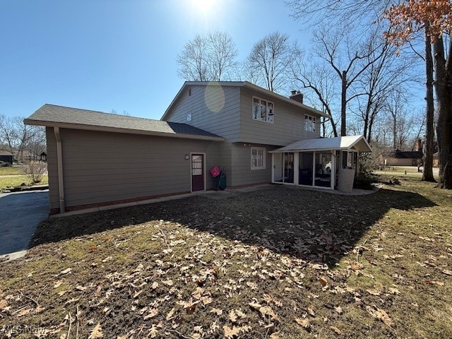 rear view of property with a sunroom and a chimney