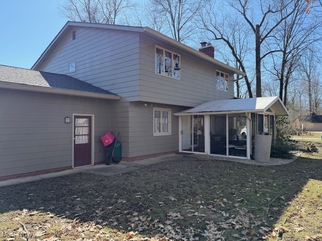 back of house featuring a chimney and a sunroom