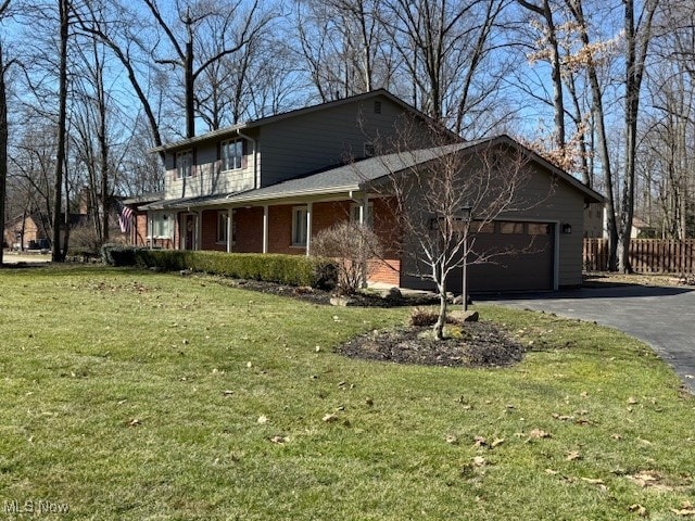 view of property exterior featuring aphalt driveway, fence, a yard, an attached garage, and brick siding