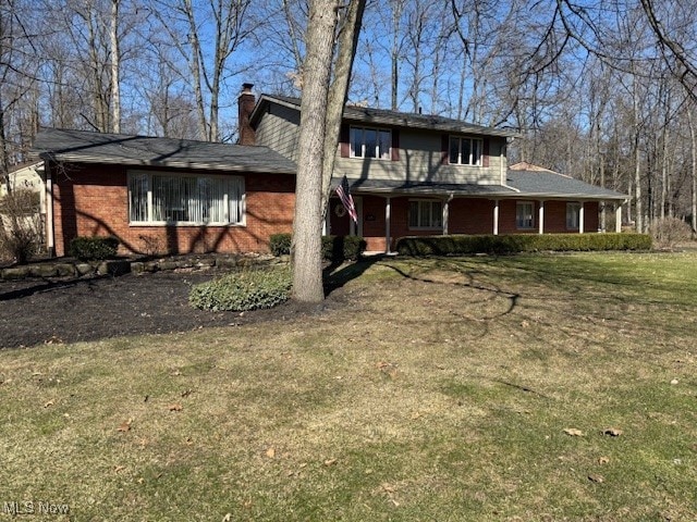 rear view of house featuring a yard, brick siding, and a chimney