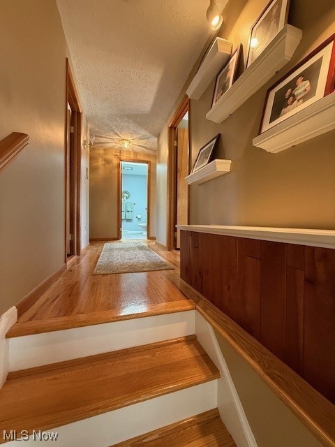 hallway with a textured ceiling and wood finished floors