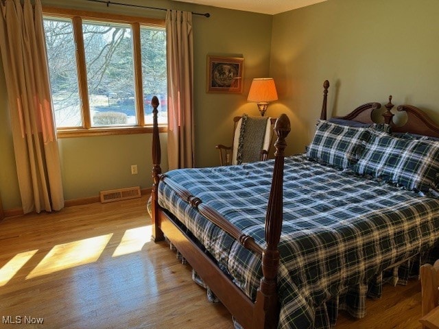 bedroom with light wood-type flooring, visible vents, and baseboards