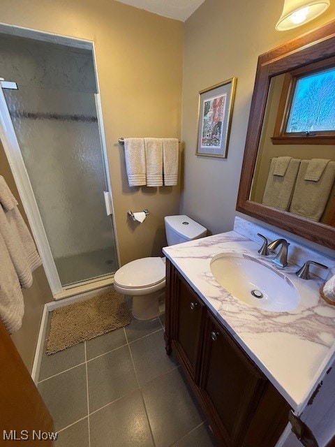 bathroom featuring tile patterned flooring, toilet, a stall shower, and vanity