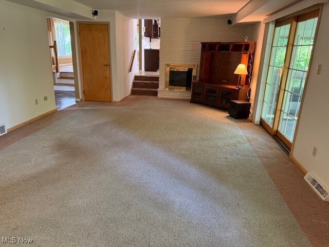 8674 Hunters Trl, Warren, OH 44484 - unfurnished living room featuring carpet floors, a glass covered fireplace, and healthy amount of natural light