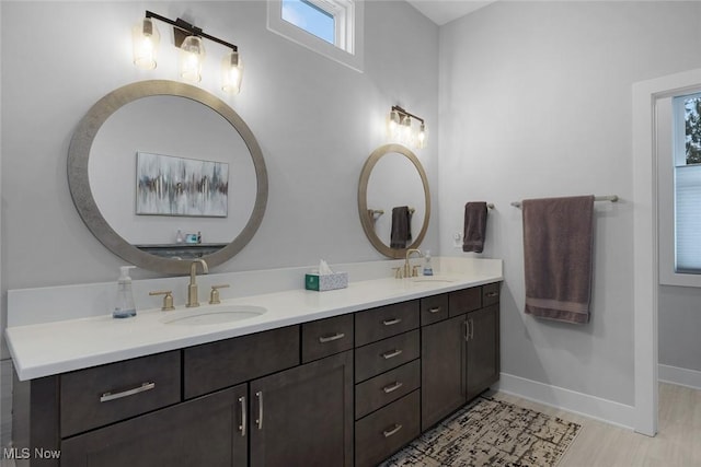 full bathroom with a sink, baseboards, and double vanity