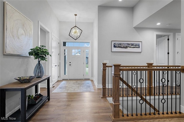 entrance foyer with recessed lighting, baseboards, a notable chandelier, and wood finished floors