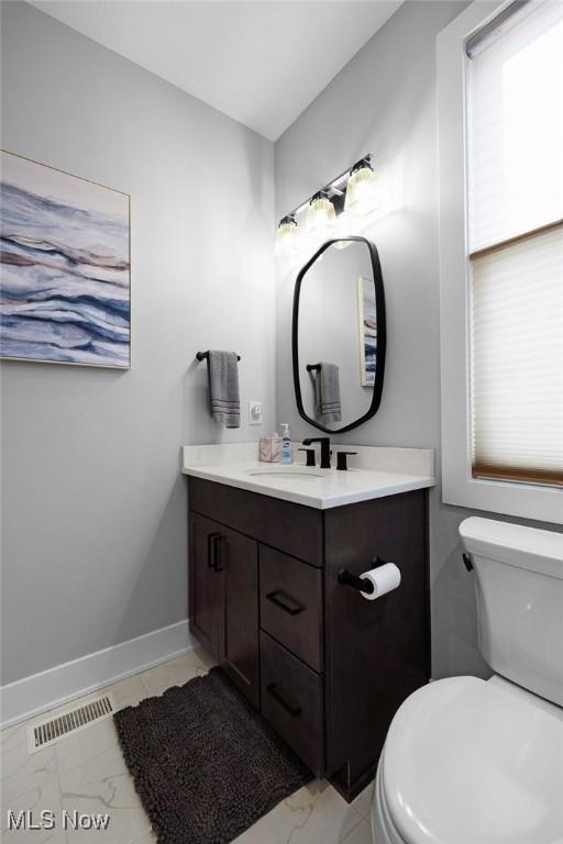 bathroom featuring toilet, baseboards, visible vents, and marble finish floor