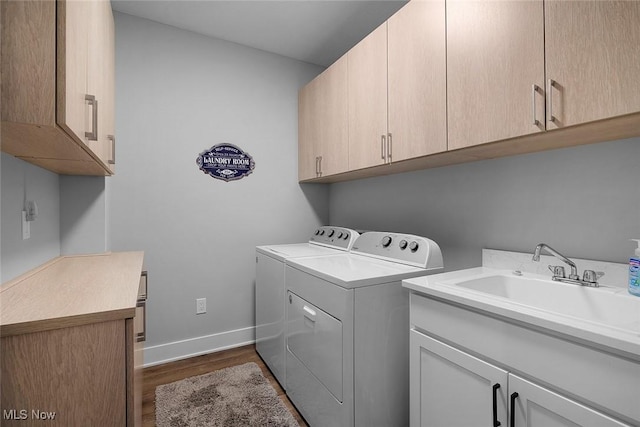 washroom with dark wood-type flooring, washer and dryer, a sink, cabinet space, and baseboards