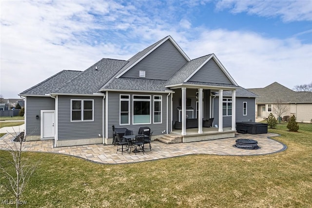 rear view of house featuring a patio area, a fire pit, a yard, and roof with shingles