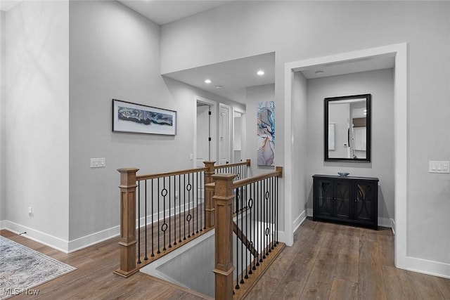 corridor with baseboards, an upstairs landing, and wood finished floors