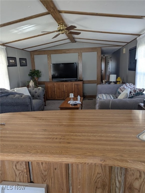 living area with lofted ceiling with beams, ceiling fan, and carpet flooring