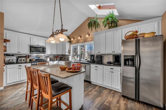 kitchen with a center island, appliances with stainless steel finishes, white cabinetry, and dark wood-style flooring